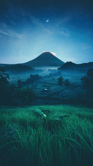 Mountain at night with crescent moon and stars