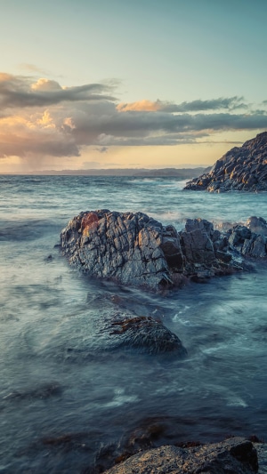 Rocky coastline with waves at sunset