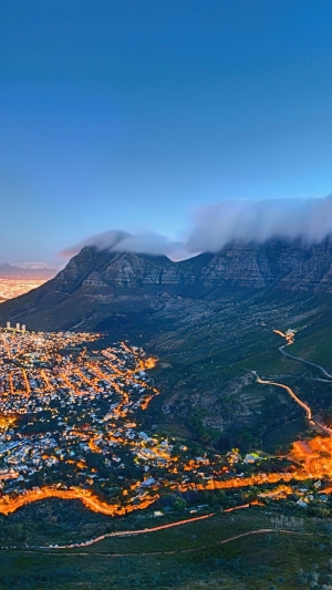 City lights at the base of a cloudy mountain