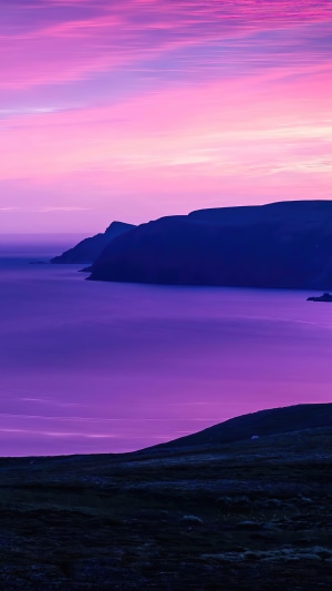 Purple sunrise over a calm sea and rocky coast