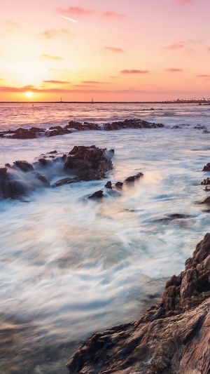Sunset over the ocean with rocks at Corona Del Mar, California