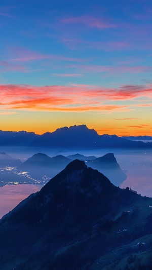 Mountain range at sunrise with lake and city lights