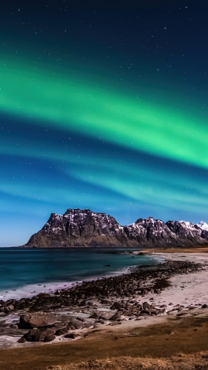 Aurora Borealis over a Norwegian beach and mountains