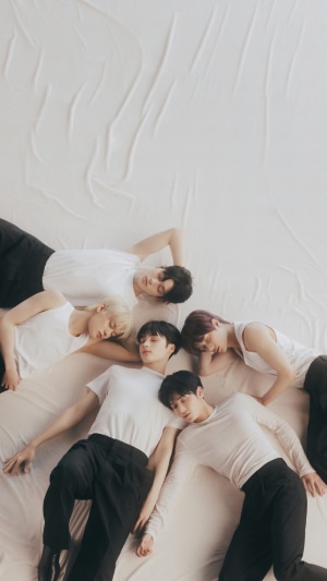 TXT members lying on a white sheet