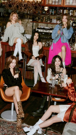 Fromis 9 posing in a bar setting