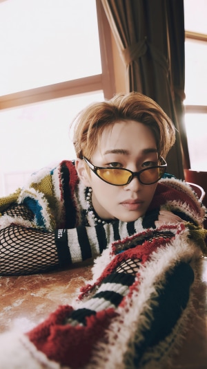 Onew wearing sunglasses and a colorful sweater