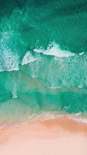 Aerial view of ocean waves crashing on a sandy beach