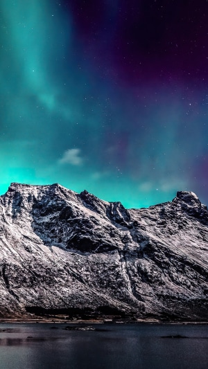 Aurora Borealis over snow-capped mountains and lake