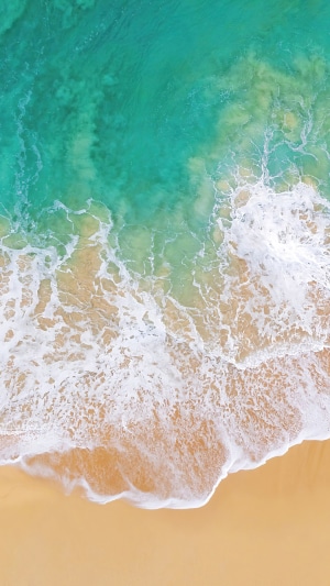 Aerial view of ocean waves crashing on a sandy beach