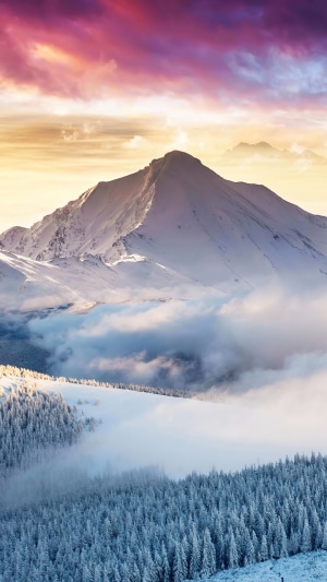 Snowy mountain peak at sunrise with colorful clouds