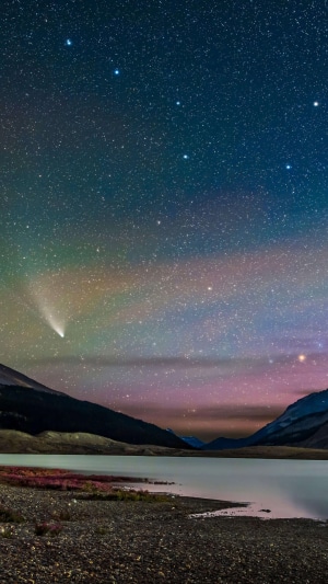 Comet over a lake and mountains at night