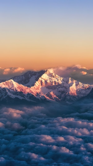 Snow-capped mountains at sunrise above clouds