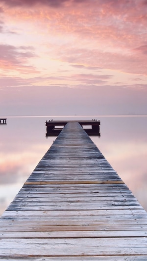 Wooden pier extending into a calm sea at sunset