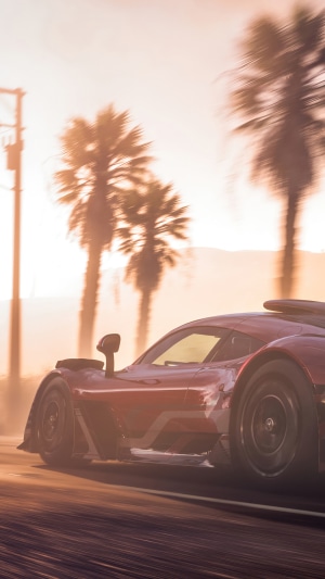 Red sports car driving on a road with palm trees