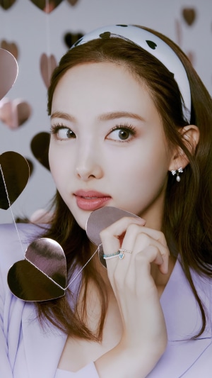 Nayeon from TWICE wearing a headband and holding heart decorations