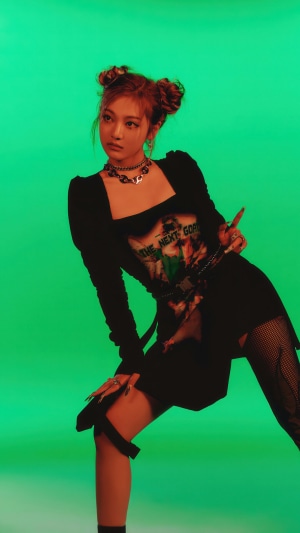 Ningning from Aespa posing in front of a green background