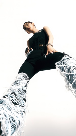 Karina from Aespa wearing black outfit with white fringe pants