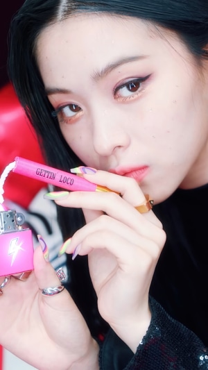 Ryujin from ITZY holding a pink lighter with 'GETTIN LOCO' text
