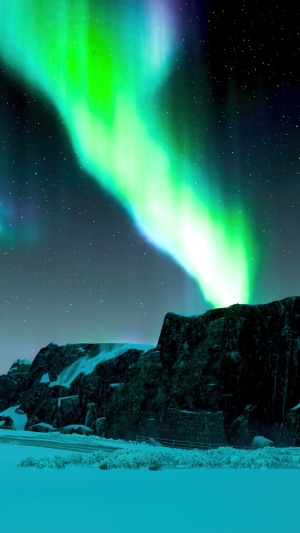 Aurora Borealis over snowy mountains at night