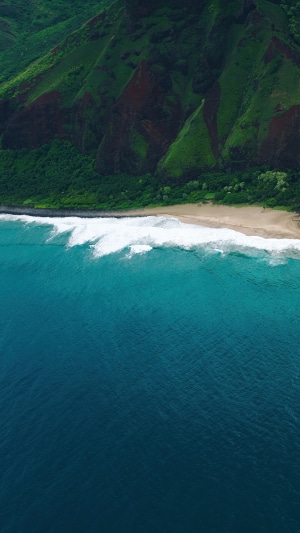 Aerial view of Hawaii coastline with green mountains and blue ocean