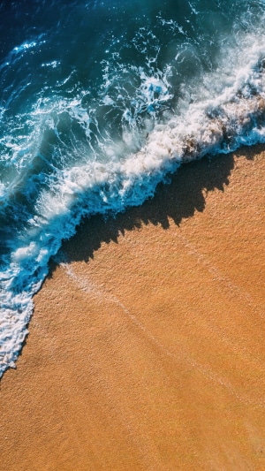 Aerial view of ocean waves crashing on a sandy beach