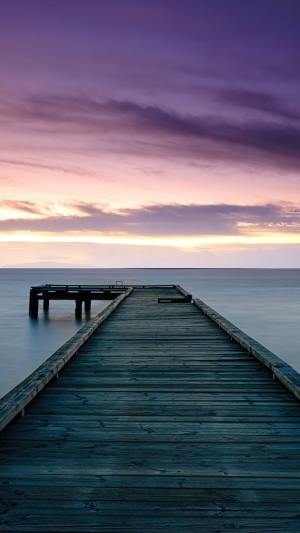 Wooden pier extending into the sea at sunset