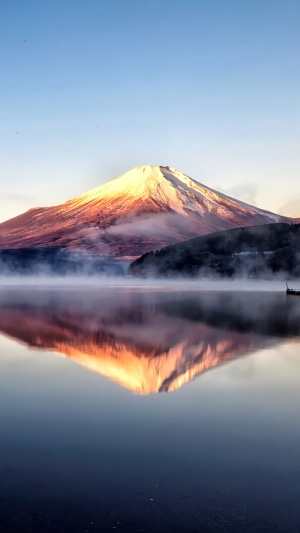 Mount Fuji reflected in a misty lake at sunrise