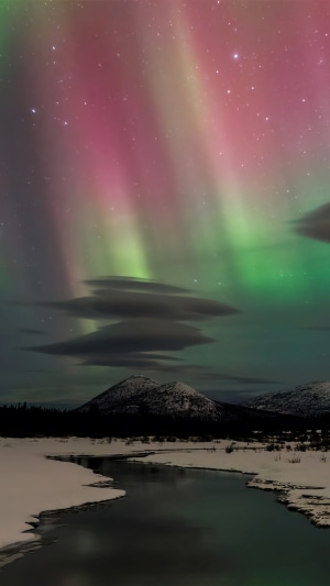 Aurora Borealis over snowy landscape with mountains