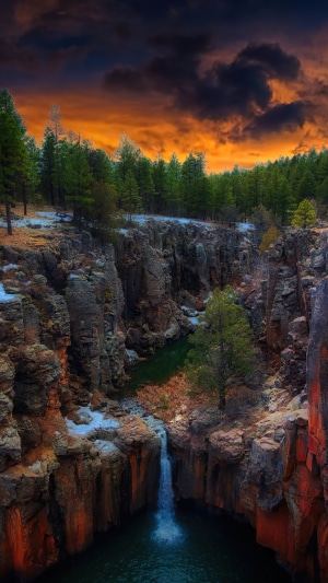 Waterfall in a forest canyon at sunset