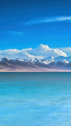 Turquoise lake with snow-capped mountains under a blue sky