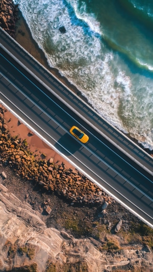 Yellow car on a coastal road aerial view