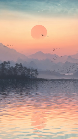 Sunset over a misty lake with mountains and birds