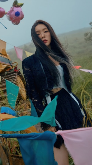 Irene from Red Velvet in a dark outfit with flags