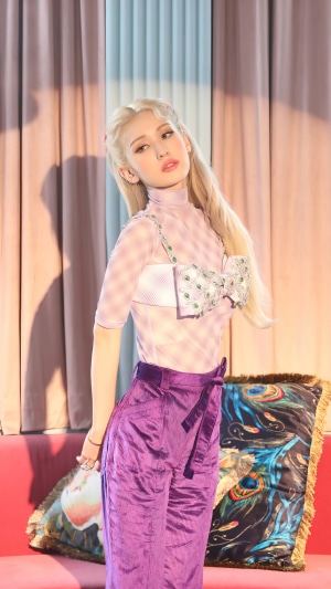 Jeon Somi posing in purple pants and a bow top