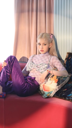 Somi from Kpop sitting on a red couch