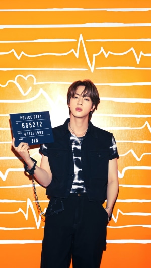 Jin from BTS holding a mugshot sign