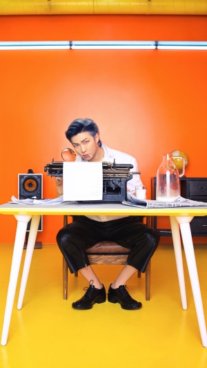 RM from BTS sitting at a desk with a typewriter