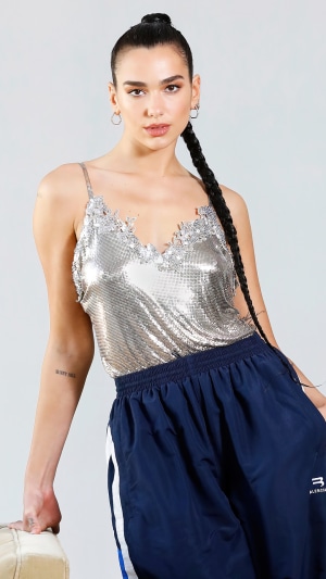 Dua Lipa wearing a silver top and blue pants