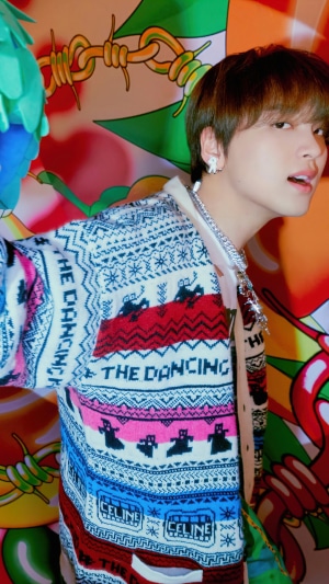Haechan from NCT Dream wearing a colorful cardigan