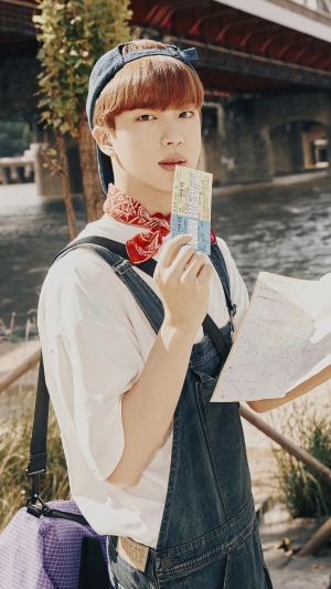 Jin from BTS holding tickets and a map