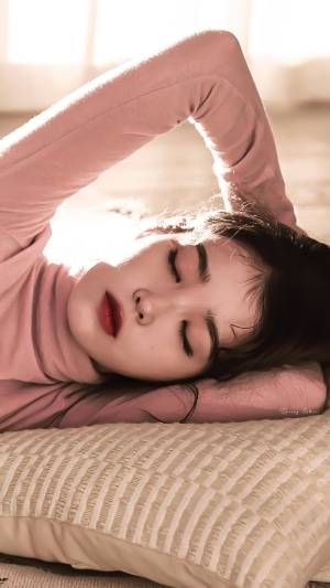 IU (Lee Ji Eun) lying down wearing a pink turtleneck