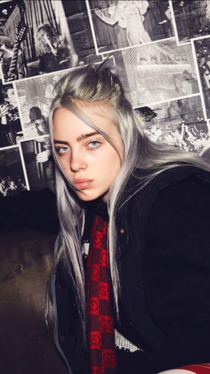 Billie Eilish with posters in the background