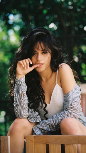 Camila Cabello sitting outdoors with hand to mouth