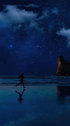 Person jogging on a beach at night under the stars