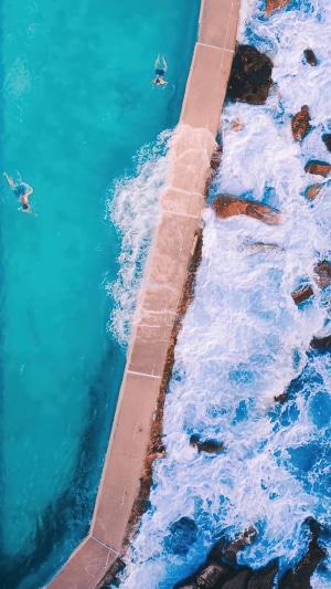 Aerial view of people swimming in a pool next to the ocean