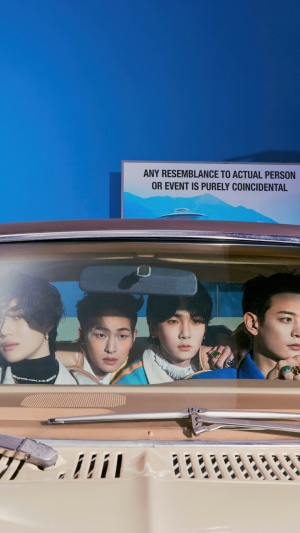 Shinee members in a car with a sign in the background