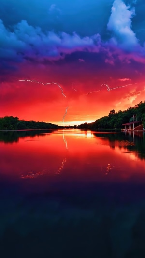 Lightning strikes over a lake during a colorful sunset