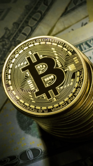 Bitcoin cryptocurrency coins stacked on US dollar bills