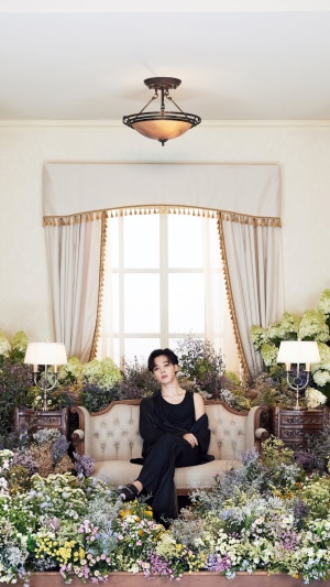 Jimin from BTS sitting in a floral setting