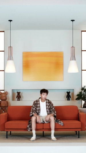 RM from BTS sitting on an orange couch